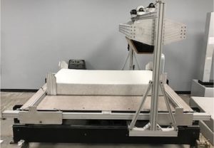 Laboratory machine applying repeated load to mattress for ASTM F1566 testing