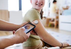 Diabetic girl with a CGM sensor on her arm.