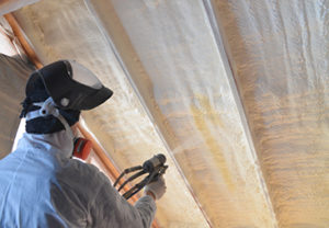 Spray Foam Insulation Applied During Construction Contractor applying spray polyurethane foam insulation inside a residential roof assembly