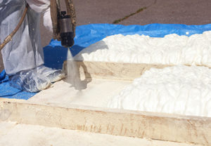 Technician applying spray polyurethane foam during insulation product installation
